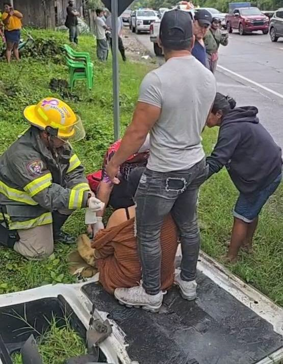 Bombero y otras personas brindan asistencia a una persona en el lugar de un accidente de tránsito en Taulabé, Comayagua.